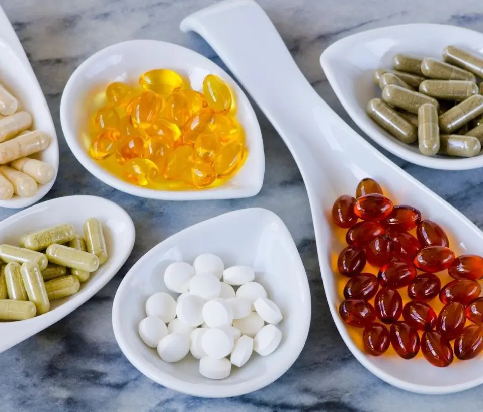 A table topped with bowls filled with pills and supplements.
